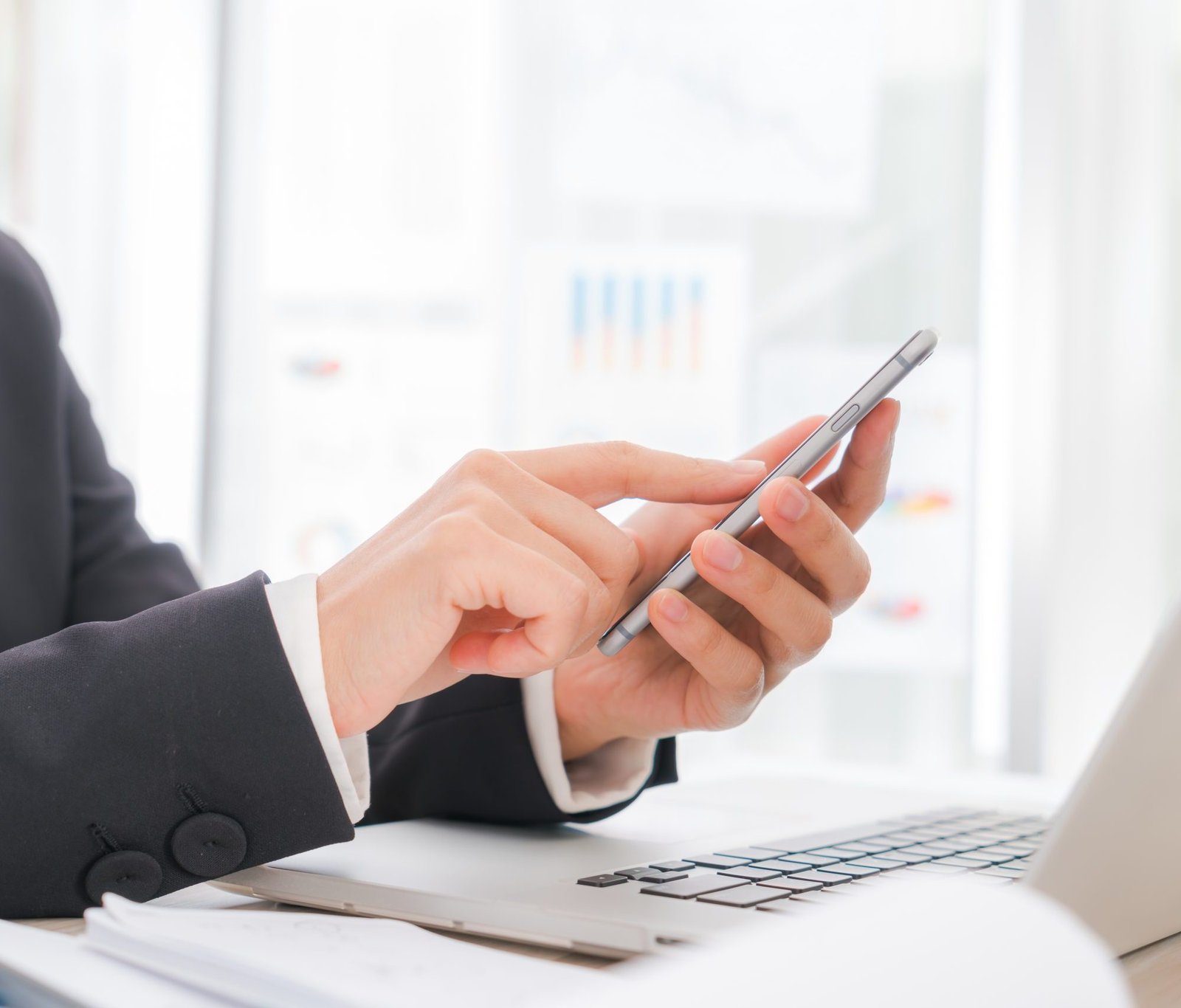 Closeup of business woman hand typing on laptop keyboard with  mobile phone
